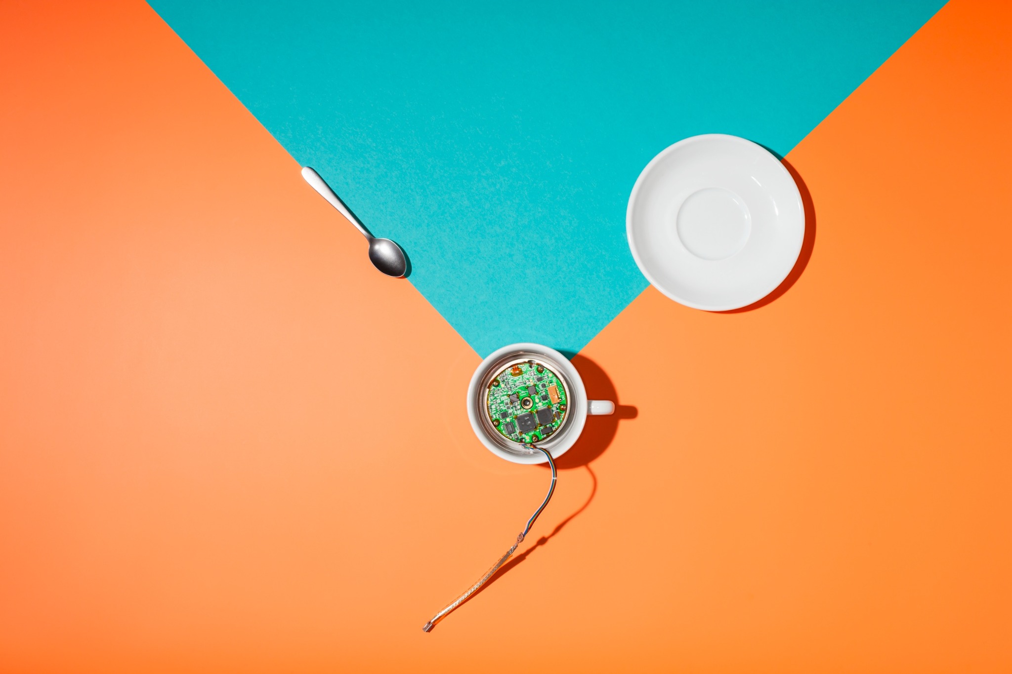 Geöffnete Kaffeetasse mit elektronischer Platine, verbunden über ein Kabel